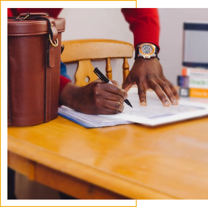 A person writing on paper with a pen and pencil.